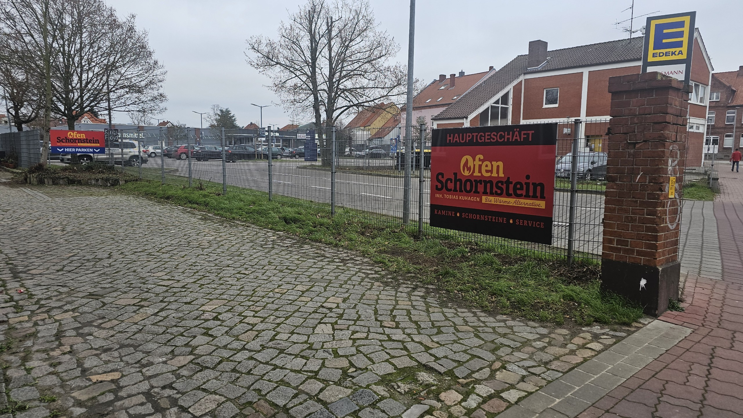 Ladenschild an Parkplatzzaun